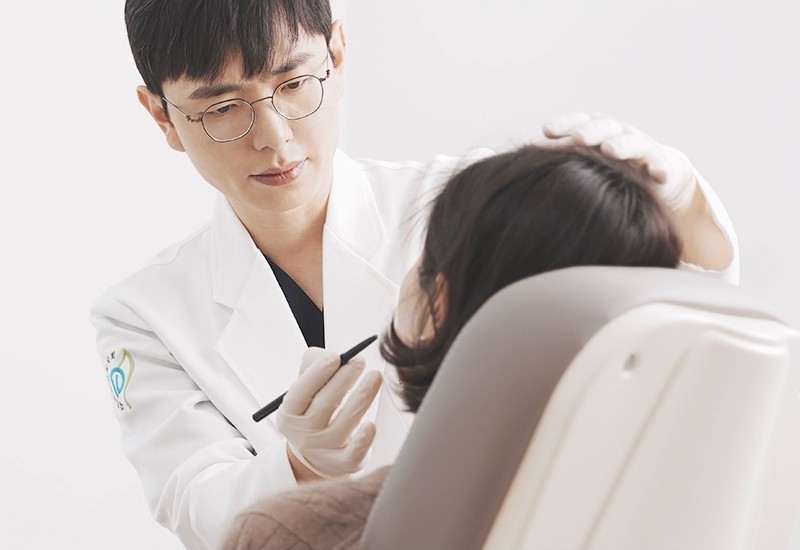 Dr. Junhyuk Seo, Medical Director, examining a patient’s skin