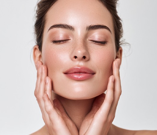 Front view of a woman cupping her face with both hands